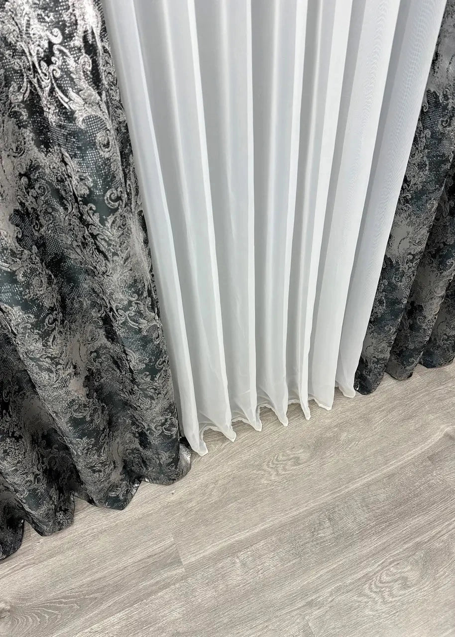 Black and grey linen curtains illuminated by warm evening lighting, enhancing their texture.