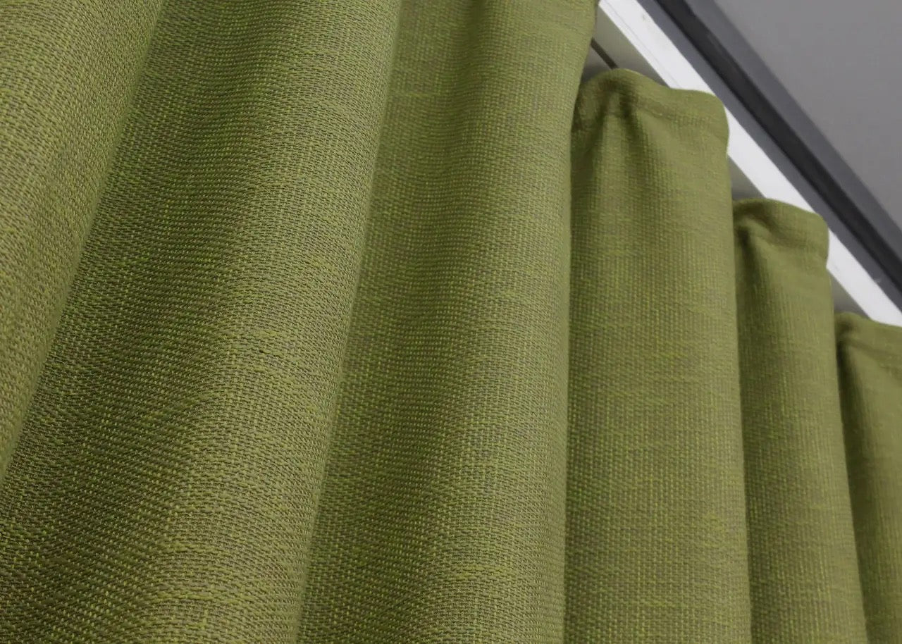 Farmhouse-style light green linen drapes, offering light diffusing properties for a calm and inviting atmosphere.
