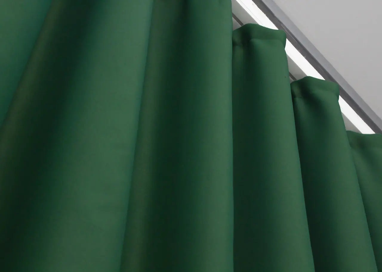 Deep sage blackout curtains providing a soft yet structured drape.

