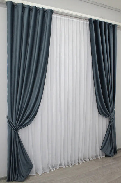 Soft dark grey-blue velvet drapes that block light and provide a cozy, serene atmosphere in living rooms and bedrooms.
