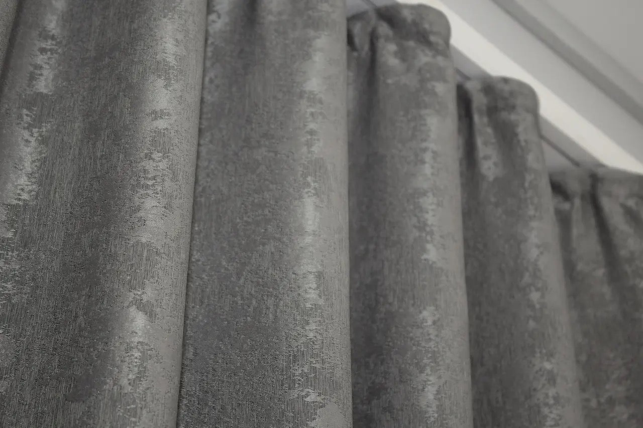 Sophisticated grey jacquard curtains with a textured woven pattern, creating a luxurious yet cozy atmosphere.
