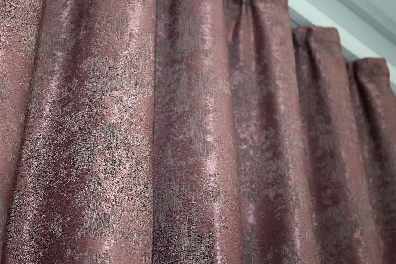 Rich raspberry grey jacquard curtains with a textured woven pattern, creating a luxurious yet warm and inviting atmosphere.
