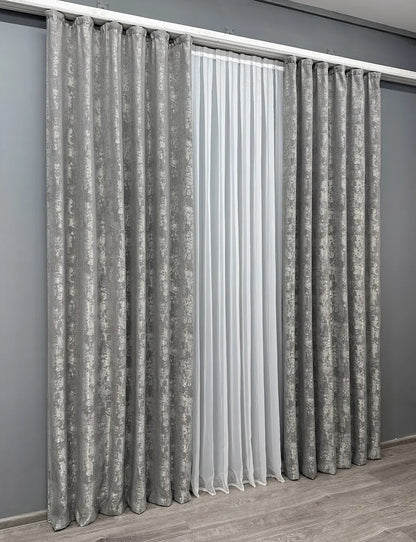 Set of two metallic silver jacquard curtain panels with matching tie-backs, creating a polished and luxurious window treatment.
