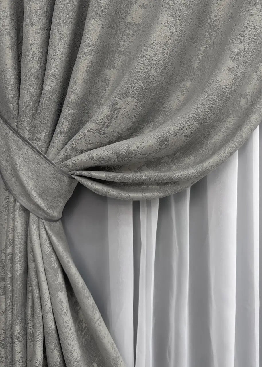 Close-up of silver jacquard curtains showcasing a luxurious woven texture and elegant metallic sheen.

