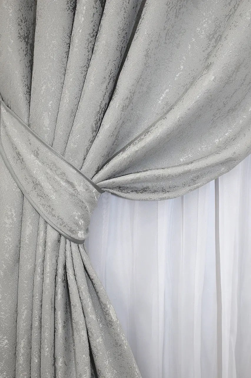 Soft silver linen drapes with a marble effect, offering privacy while maintaining a light and elegant atmosphere.
